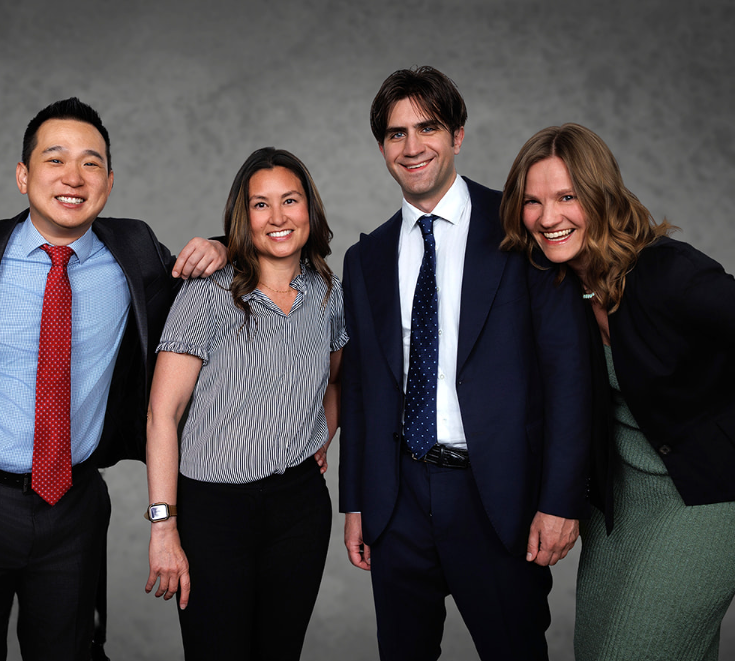 Four Insight Economics team members in professional business attire posing together, representing the expert economists and consultants who deliver the firm's services.