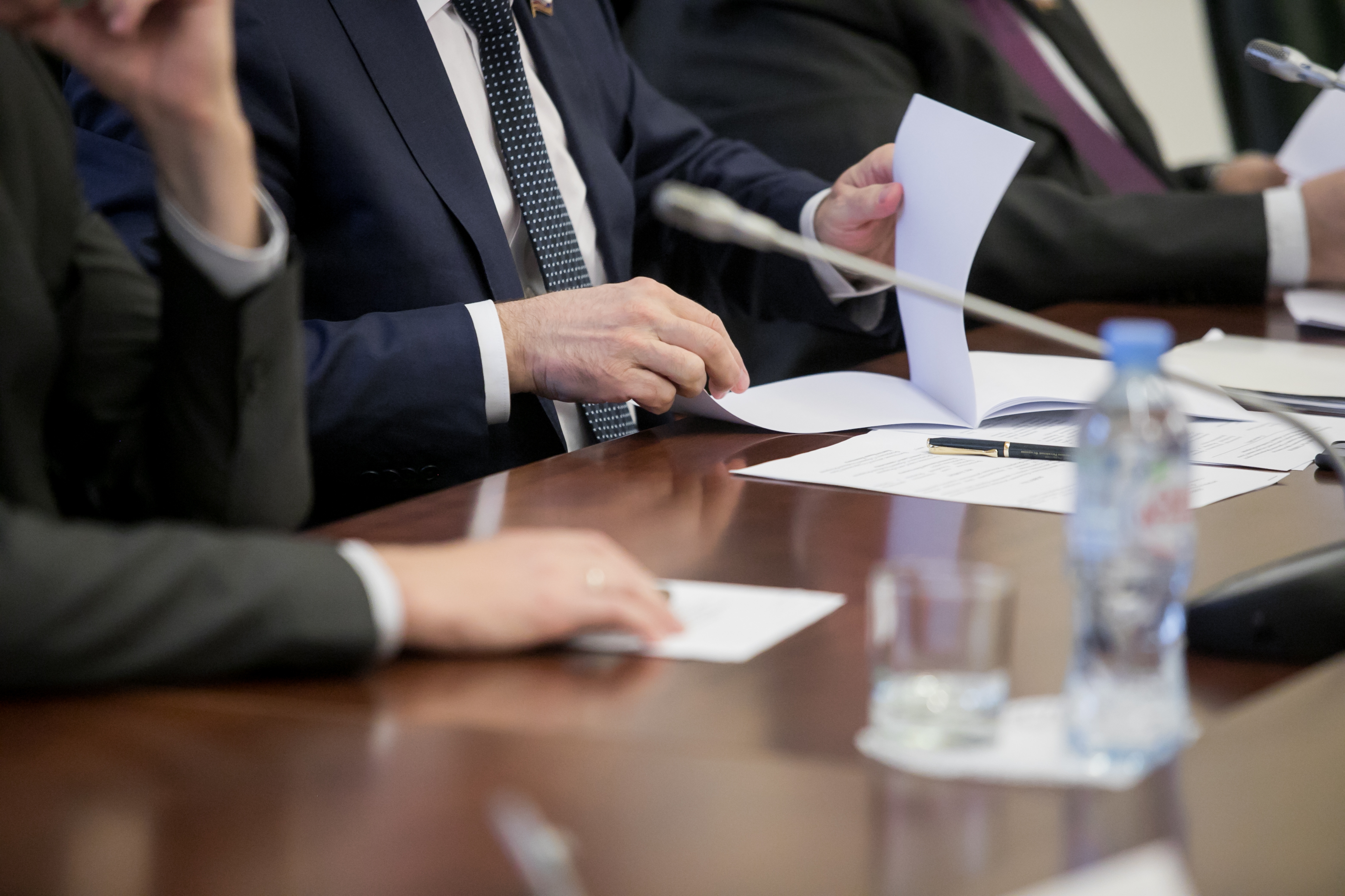 Close-up of lawyers reviewing documents at a conference table during a formal hearing, representing the expert witness testimony environment Insight Economics operates in.