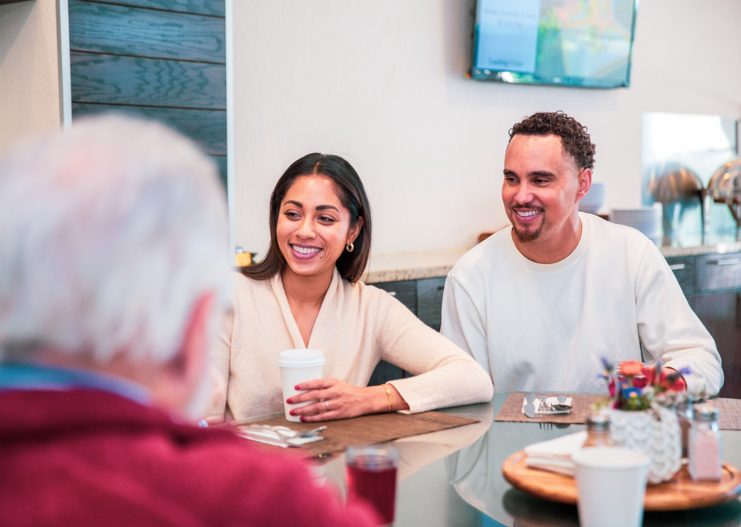 A smiling couple seated at a table in conversation with a physician across from them, representing the patient intake and Become a Patient pathway built into the Oasis of Hope website to give prospective patients and families a clear, human first step toward care.